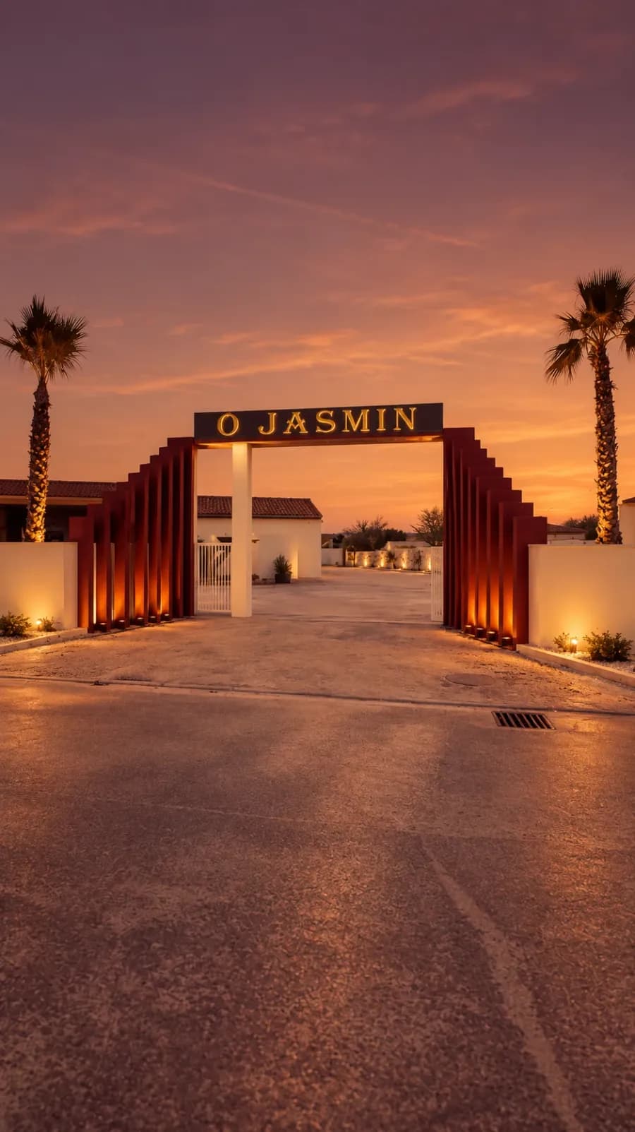 Le portail de la salle O Jasmin au crépuscule, entre deux palmiers